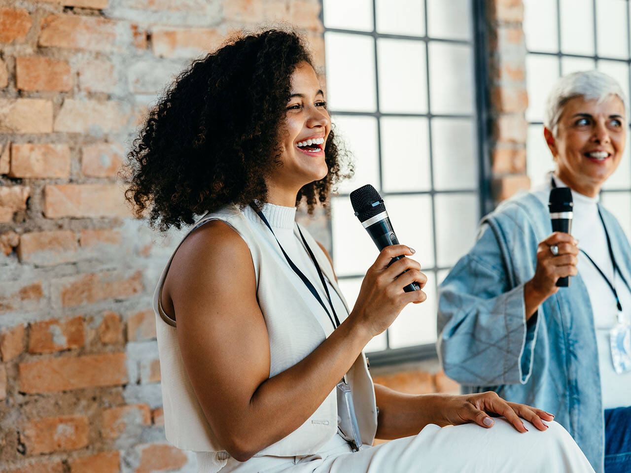 Two excited african american and caucasian females speaking on a corporate panel discussion